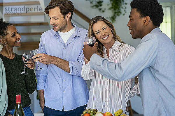 Eine Gruppe von Freunden stößt mit Weingläsern an  während sie drinnen hängt