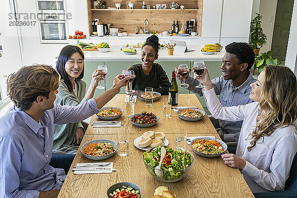 Eine Gruppe von Freunden stößt beim Abendessen mit Weingläsern an
