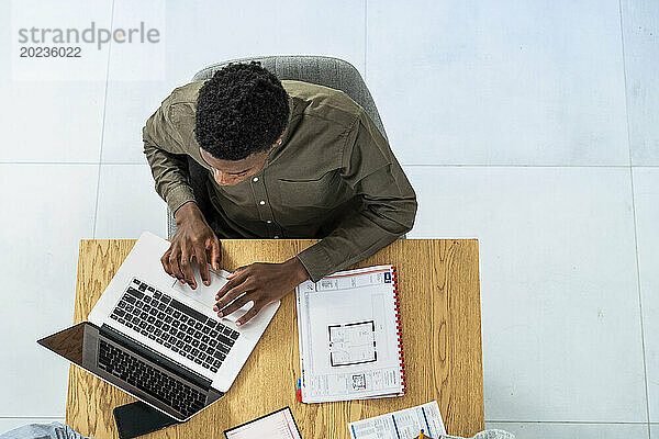 Zenithaler Blick auf einen Geschäftsmann  der am Schreibtisch am Laptop arbeitet