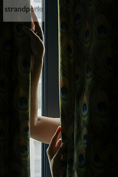 Der Arm einer unbekannten Person öffnet ein Fenster
