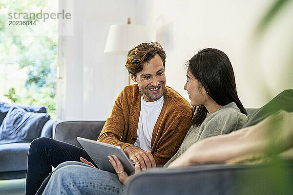 Erwachsenes Paar hat Spaß beim Benutzen eines digitalen Tablets auf dem Sofa