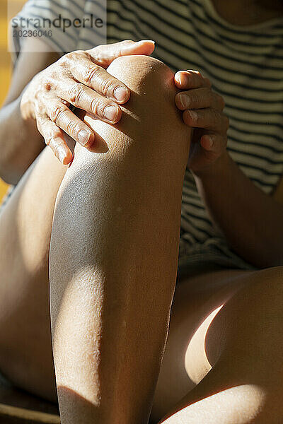 Die Hände einer unbekannten Person berühren ihre Beine