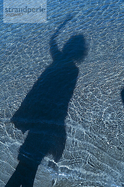 Shadow of unidentified person on blue water