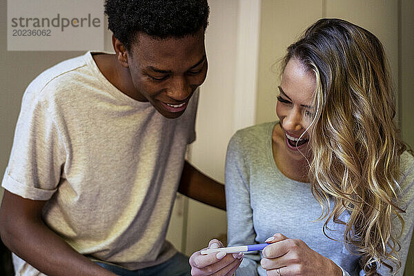 Glückliches Paar jubelt  während es einen Schwangerschaftstest hält