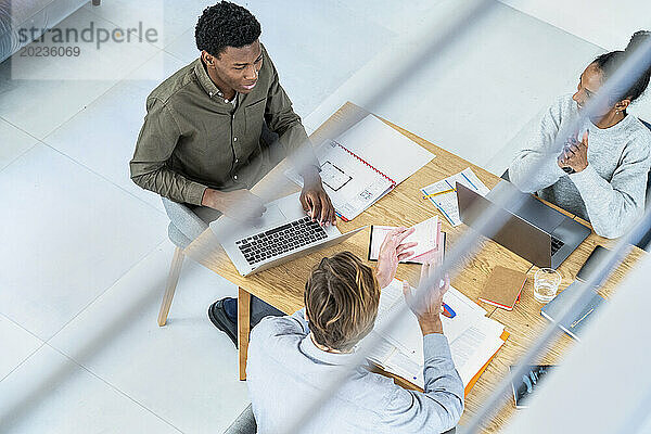 Geschäftsleute und Geschäftsfrau diskutieren am Schreibtisch mit Laptop über Arbeit