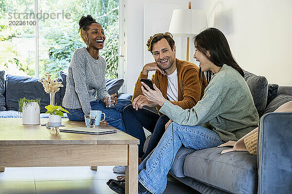 Small group of friends having fun while hanging on living room
