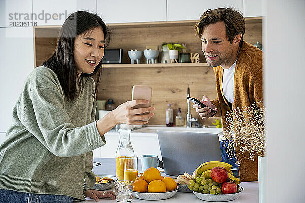 Erwachsenes Paar spricht beim Frühstück über Smartphone