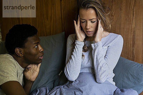 Erwachsene Frau hat Kopfschmerzen  während sie mit ihrem Freund im Bett spricht