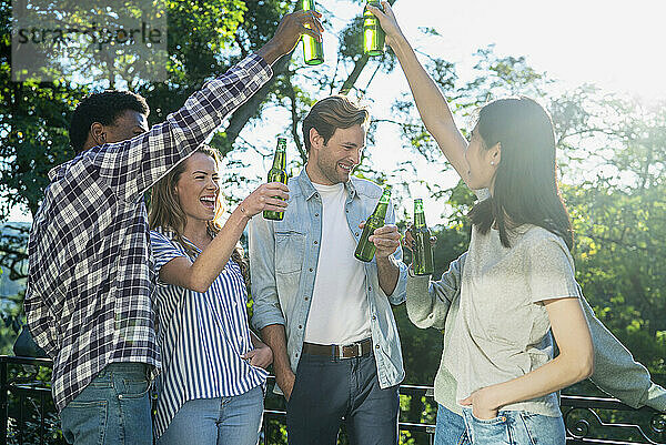 Group of friends toasting with beer bottles standing outdoors