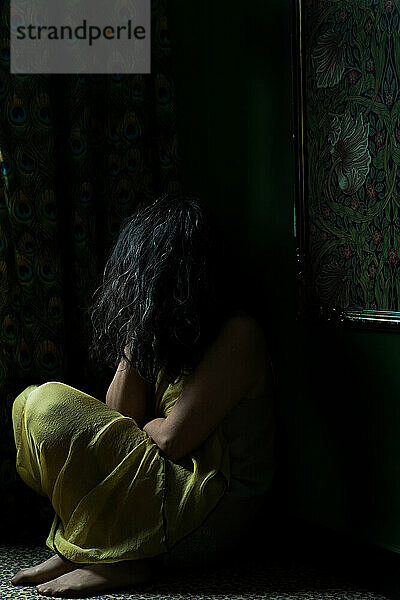 Unidentified person sitting on floor in dark room