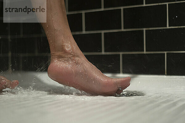 Der nackte Fuß einer unbekannten Person in der Dusche