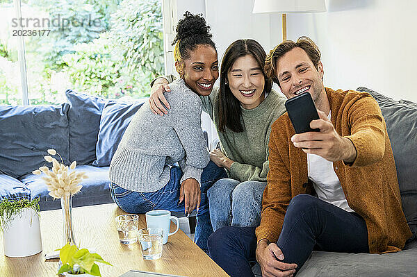 Kleine Gruppe Freunde machen ein Selfie  während sie auf dem Sofa sitzen