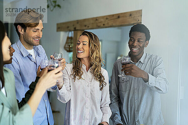 Gruppe von Freunden feiert Toasten mit Weingläsern im Wohnzimmer