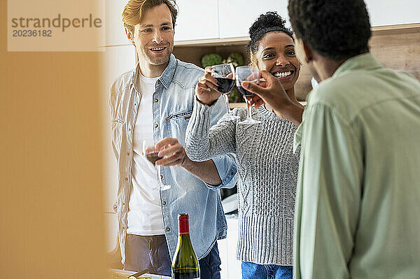Freunde stoßen beim Wiedersehen in der Küche mit Weingläsern an