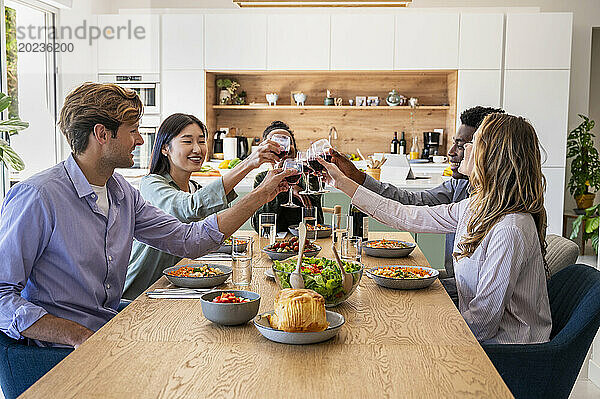 Eine Gruppe von Freunden stößt beim Abendessen mit Weingläsern an