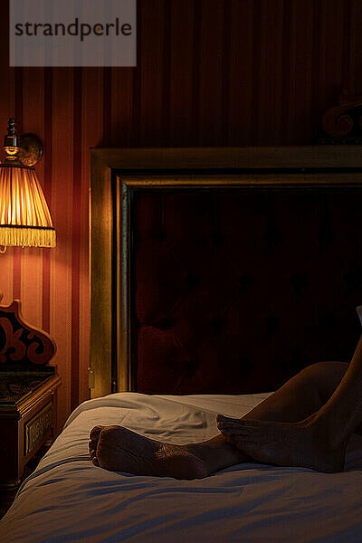 Unidentified person's legs lying on bed in dark bedroom