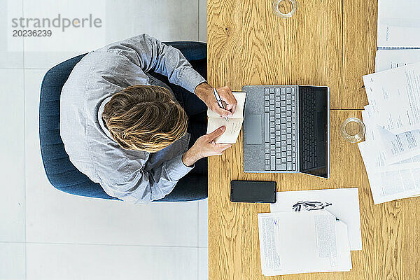 Advertising agency worker taking notes while sitting at desk