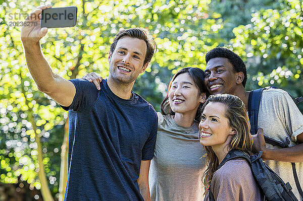 Junger erwachsener Mann macht beim Wanderausflug ein Selfie mit Freunden