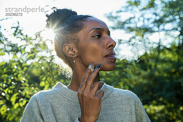 Adult woman smoking while standing outdoors during day time