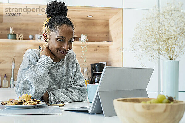 Frau hält eine Webkonferenz auf einem digitalen Tablet in der Küche ab