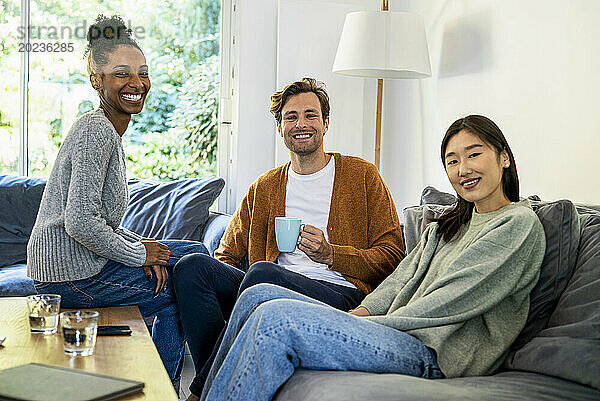 Small group of friends gathered in living room looking at the camera