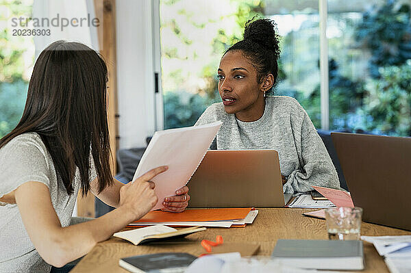 Zwei Frauen diskutieren über Papierkram und Laptop