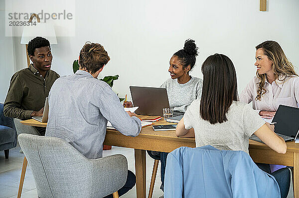 Coworkers gathered in office while working on laptops