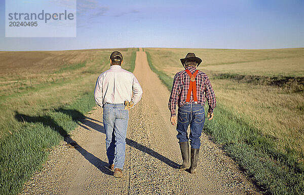 Rancher und sein Sohn gehen eine Schotterstraße entlang; Howes  South Dakota  Vereinigte Staaten von Amerika