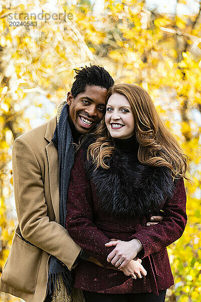 Nahaufnahme eines verheirateten Paares gemischter Abstammung  das in die Kamera lächelt  während es bei einem Familienausflug im Herbst in einem Stadtpark schöne Zeit miteinander verbringt; Edmonton  Alberta  Kanada