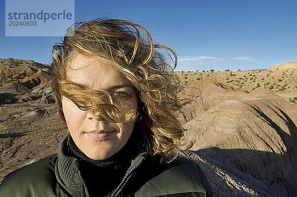 Außenporträt einer jungen Frau mit lockigem Haar  die auf einem Felsvorsprung auf der Ghost Ranch in der Nähe von Santa Fe posiert; New Mexico  Vereinigte Staaten von Amerika