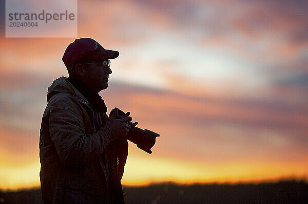 Silhouette eines Mannes draußen mit einer Kamera bei Sonnenuntergang; Valentine  Nebraska  Vereinigte Staaten von Amerika