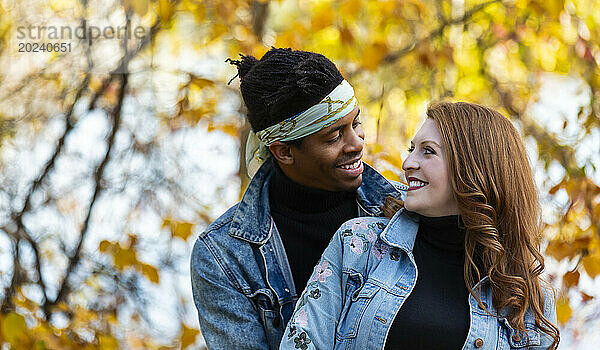 Nahaufnahme eines gemischtrassigen Ehepaares  das einander anlächelt und bei einem Familienausflug im Herbst in einem Stadtpark schöne Zeit miteinander verbringt; Edmonton  Alberta  Kanada