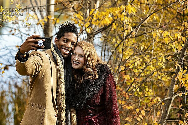 Nahaufnahme eines gemischtrassigen Ehepaares  das ein Selfie macht  während es bei einem Familienausflug im Herbst in einem Stadtpark schöne Zeit miteinander verbringt; Edmonton  Alberta  Kanada