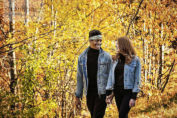 Nahaufnahme eines gemischtrassigen Ehepaares  das einander anlächelt  während eines Familienausflugs im Herbst durch einen Stadtpark spaziert und schöne Zeit miteinander verbringt; Edmonton  Alberta  Kanada