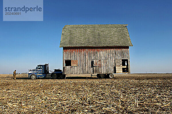 Barn being moved on a dirt road in the countryside in rural Nebraska  USA; Dunbar  Nebraska  United States of America