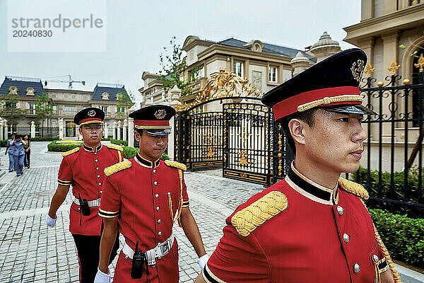 Chinesische Wachen tragen rote Jacken mit goldenen Schulterklappen  Mützen und Walkie-Talkies an weißen Gürteln  während sie sich an der Palais de Fortune-Siedlung außerhalb von Peking  China  aufhalten; Volksrepublik China