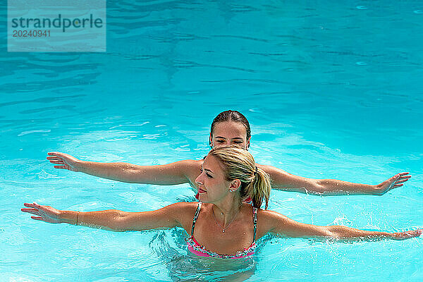 2 junge Frauen springen mit schwingenden Armen ins Wasser