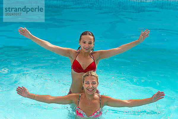 2 junge Frauen springen mit schwingenden Armen ins Wasser