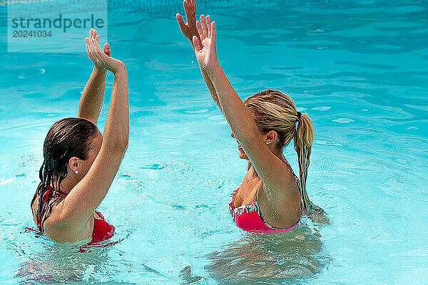 2 junge Frauen springen mit schwingenden Armen ins Wasser