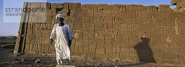 Sudanesischer Mann steht neben ägyptischen Ruinen  einem nubischen Königsgrab aus der 25. Dynastie. El-Kurru war einer der königlichen Friedhöfe  die von der nubischen Königsfamilie genutzt wurden. Der Zerfall des ägyptischen Reiches begann im Jahr 1000 v. Chr. und im Jahr 660 v. Chr. herrschte das Königreich Kusch über ein Reich  das sich vom Zentralsudan bis zu den Grenzen Palästinas erstreckte. Sudan