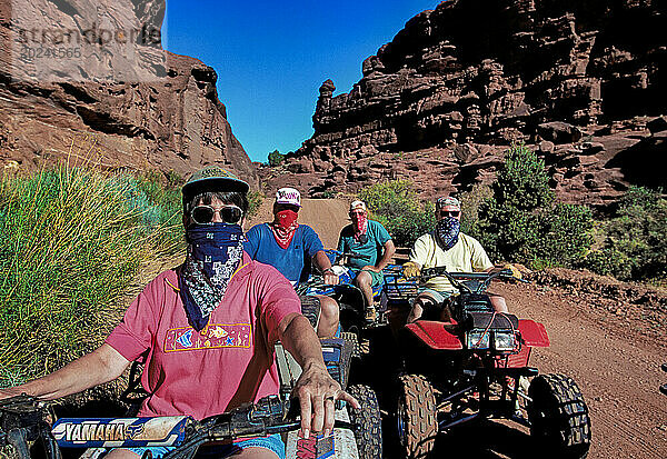 Bandanas im Banditenstil schützen Gesetzestreue auf einem ausgetretenen Pfad in der Fisher Towers-Region des Castle Valley in der Nähe von Moab  Utah  vor Staub. Es gibt viele Fahrer von Geländefahrzeugen  die sich an die locker durchgesetzten Straight-and-Narrow-Regeln der BLM halten  aber Tausende missachten die Regeln und folgen dem Ruf ihrer Verbrennungsmotoren  um neue Wege durch straßenlose Gebiete zu beschreiten. Die Verschlechterung durch illegale ATV-Fahrer hat zunehmende ökologische Folgen. In der Nähe von Moab  Utah  USA; Utah  Vereinigte Staaten von Amerika