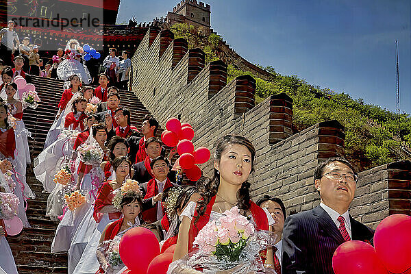 In formeller Kleidung gekleidete Paare warten auf die Massenhochzeit  die an der Chinesischen Mauer außerhalb von Peking stattfand. Manche heiraten vielleicht aus Liebe  aber die Ehe kann auch ein großer sozialer und finanzieller Fortschritt sein; Volksrepublik China