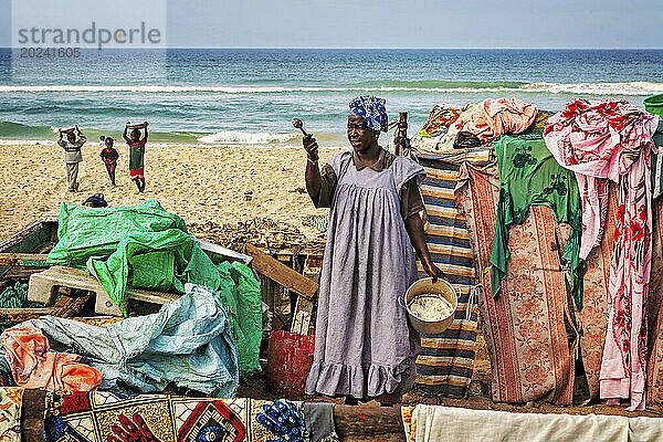 Eine Frau bereitete Essen umgeben von bunten Tüchern in der Strandsiedlung Saint Louis  Senegal  zu. Die Stadt war einst ein wichtiges Wirtschaftszentrum in Französisch-Westafrika  verfügt jedoch immer noch über wichtige Industriezweige  darunter Tourismus  ein Handelszentrum  ein Zentrum der Zuckerproduktion und der Fischerei. Saint Louis  Senegal