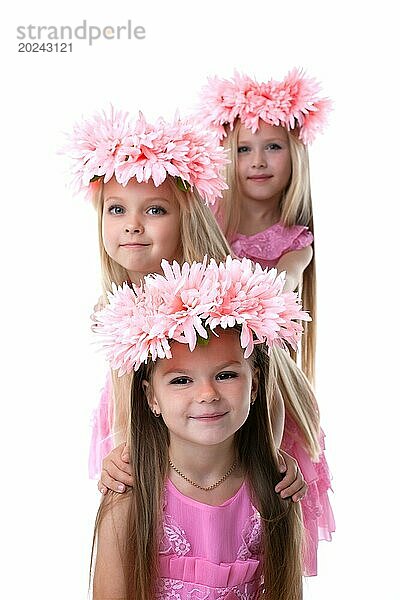 Drei hübsche kleine Mädchen mit rosa Kränzen. vor weißem Hintergrund