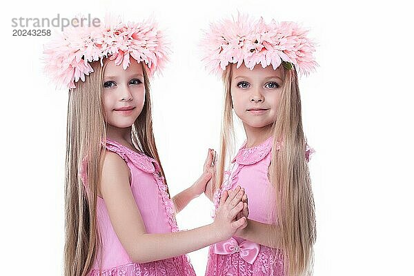 Zwei schöne kleine Mädchen in rosa Kleidern. vor weißem Hintergrund