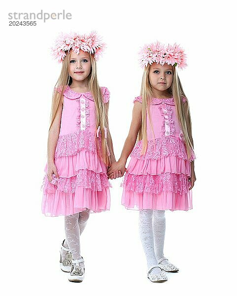 Zwei schöne kleine Mädchen in rosa Kleidern. vor weißem Hintergrund