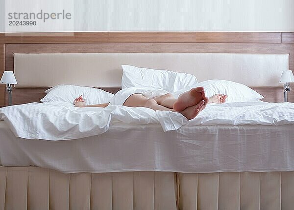 Junge Frau entspannt sich auf dem Bett eines Hotelzimmers  nur die Beine