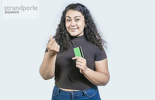 Attraktives Mädchen  das eine Kreditkarte hält und mit den Fingern eine Geldgeste macht  isoliert  mit Blick in die Kamera