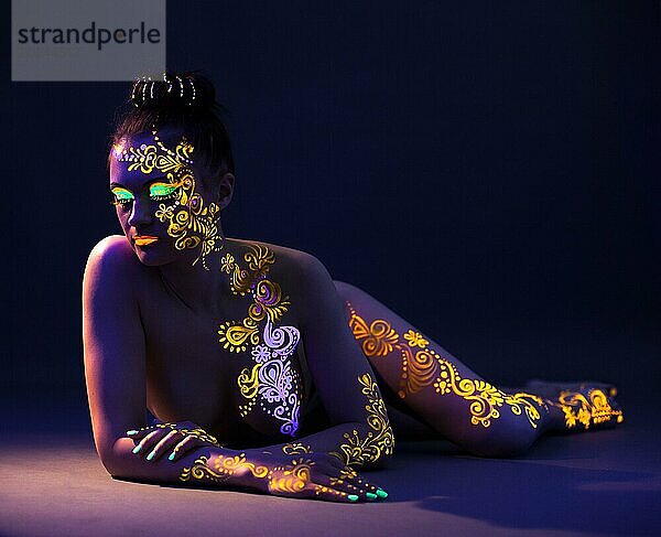 Attraktives nacktes Mädchen mit UV Makeup posiert im Studio  Nahaufnahme