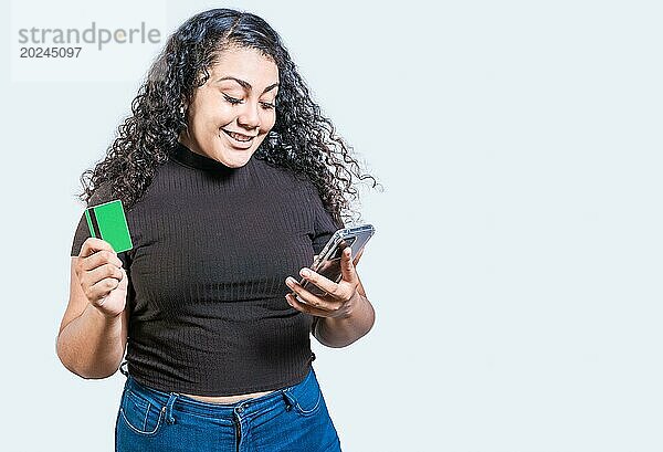 Glückliches Mädchen mit Kreditkarte beim Online Shopping mit Telefon isoliert. Person macht Online Einkäufe mit Handy und Kreditkarte isoliert